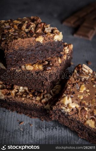 Delicious brownies with walnuts, in a stack on a wooden table. Close-up image with brownie cake sliced pieces