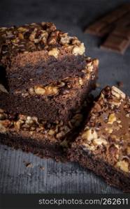 Delicious brownies with walnuts, in a stack on a wooden table. Close-up image with brownie cake sliced pieces