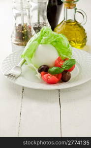 delicious buffalo mozzarella with wrapped lettuce and tomatoes on wooden table