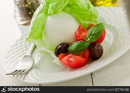 delicious buffalo mozzarella with wrapped lettuce and tomatoes on wooden table