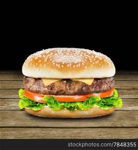 Delicious burger with beef, tomato, cheese and lettuce on wood background