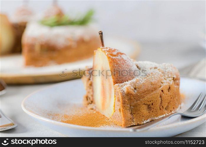 Delicious cake slice with pear, ginger and cinnamon on a plate in a dark kitchen counter.