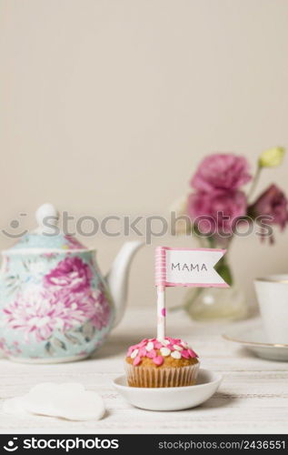 delicious cake with decorative flag with mama title near teapot flowers