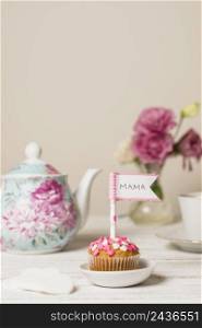 delicious cake with decorative flag with mama title near teapot flowers
