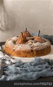 Delicious cake with pear, ginger and cinnamon on a dark kitchen counter.
