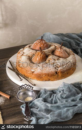 Delicious cake with pear, ginger and cinnamon on a dark kitchen counter.