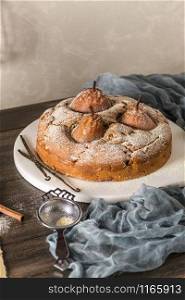 Delicious cake with pear, ginger and cinnamon on a dark kitchen counter.