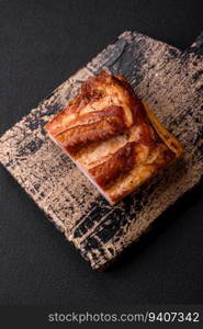 Delicious calorie smoked bacon with salt, spices and herbs on a dark concrete background