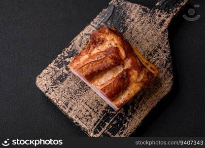 Delicious calorie smoked bacon with salt, spices and herbs on a dark concrete background