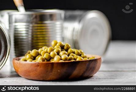 Delicious canned green peas on a plate. On a black background. High quality photo. Delicious canned green peas on a plate.