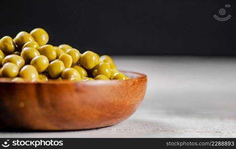 Delicious canned green peas on a plate. On a black background. High quality photo. Delicious canned green peas on a plate.