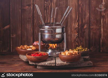 Delicious Cheese Fondue on a fork on a wooden stand. The cheese fondue