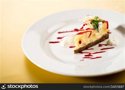 Delicious cheesecake with raspberry sauce on white plate yellow background