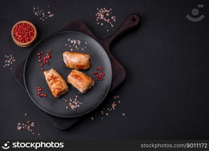 Delicious chicken or pork meat roll with mushrooms, cheese, spices and herbs on a dark concrete background