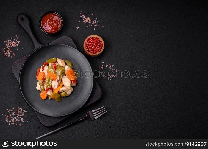 Delicious chicken slices and steamed vegetables carrots, broccoli, asparagus beans and peppers on a dark concrete background