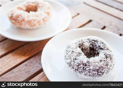 Delicious chocolate and vanilla coconut donuts on wooden table, stock photo