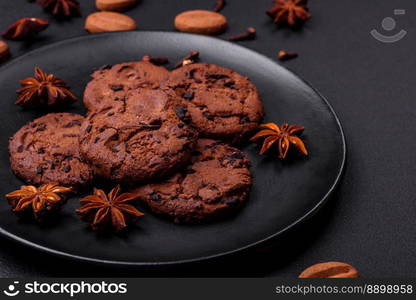 Delicious chocolate cookies with nuts on a black ceramic plate on a dark concrete background