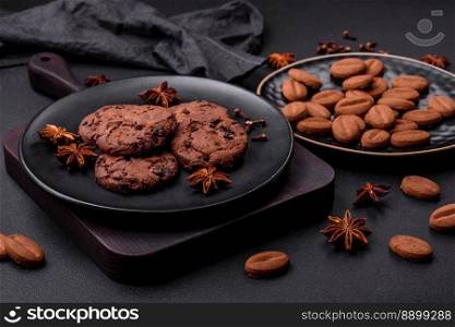 Delicious chocolate cookies with nuts on a black ceramic plate on a dark concrete background