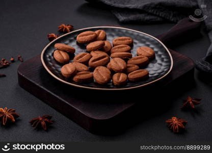 Delicious chocolate cookies with nuts on a black ceramic plate on a dark concrete background