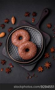 Delicious chocolate glazed donut sprinkled with chocolate chips on a dark concrete background
