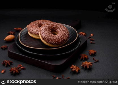 Delicious chocolate glazed donut sprinkled with chocolate chips on a dark concrete background