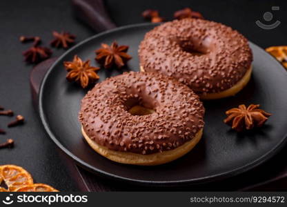 Delicious chocolate glazed donut sprinkled with chocolate chips on a dark concrete background