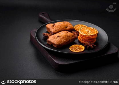 Delicious chocolate muffins and dried round shaped slices of bright orange color tangerine on a dark textural background