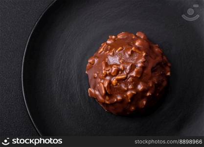 Delicious chocolate tart with nuts on a black ceramic plate on a dark concrete background
