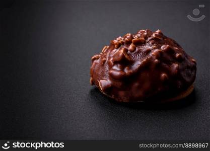 Delicious chocolate tart with nuts on a black ceramic plate on a dark concrete background