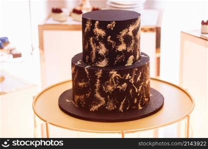 delicious chocolate two-tier birthday cake with gold decorations. candy bar.. delicious chocolate two-tier birthday cake with gold decorations. candy bar