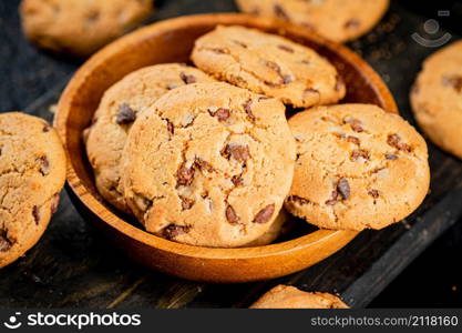 Delicious cookies with pieces of milk chocolate on a plate. On a black background. High quality photo. Delicious cookies with pieces of milk chocolate on a plate.