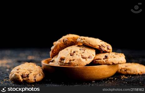 Delicious cookies with pieces of milk chocolate on a plate. On a black background. High quality photo. Delicious cookies with pieces of milk chocolate on a plate.