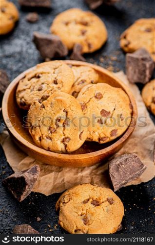 Delicious cookies with pieces of milk chocolate on a plate. On a black background. High quality photo. Delicious cookies with pieces of milk chocolate on a plate.