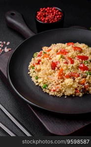 Delicious couscous porridge with cubes of grilled vegetables with salt and spices on a dark concrete background