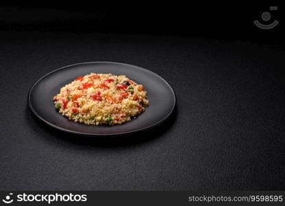 Delicious couscous porridge with cubes of grilled vegetables with salt and spices on a dark concrete background