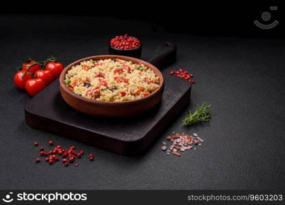 Delicious couscous porridge with cubes of grilled vegetables with salt and spices on a dark concrete background