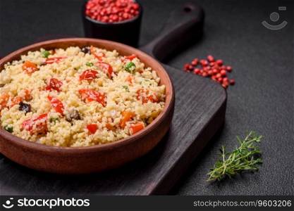 Delicious couscous porridge with cubes of grilled vegetables with salt and spices on a dark concrete background
