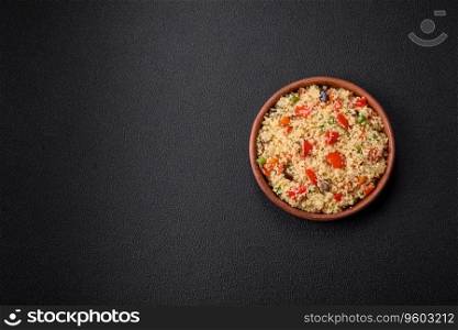 Delicious couscous porridge with cubes of grilled vegetables with salt and spices on a dark concrete background