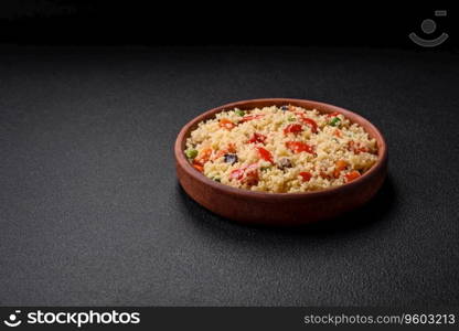 Delicious couscous porridge with cubes of grilled vegetables with salt and spices on a dark concrete background