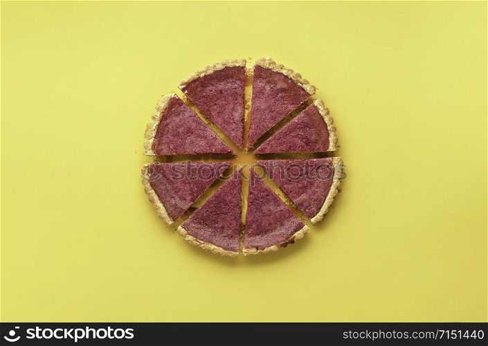 Delicious cranberry pie sliced in portions on a yellow background. Above view with berries tart slices. Divided pie chart concept. Christmas dessert.