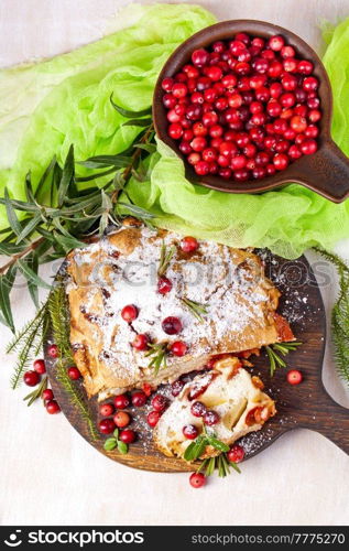 Delicious cranberry pie with fresh cranberries and herbs for Christmas on wooden plate.