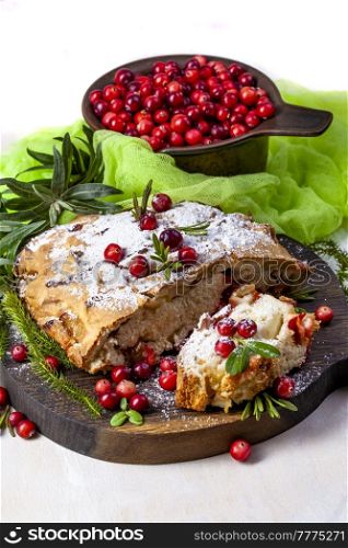 Delicious cranberry pie with fresh cranberries and herbs for Christmas on wooden plate.