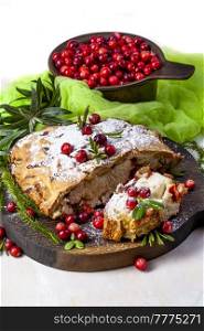 Delicious cranberry pie with fresh cranberries and herbs for Christmas on wooden plate.