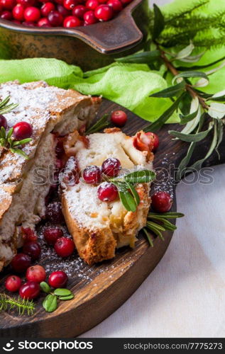 Delicious cranberry pie with fresh cranberries and herbs for Christmas on wooden plate.