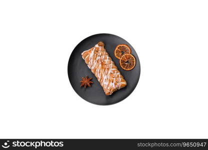 Delicious crispy braided bun with raisins inside and white icing outside on a dark concrete background