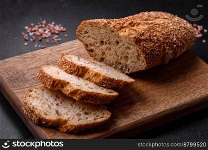  Delicious crispy bread with cereals cut into slices on a wooden cutting board on a dark concrete background