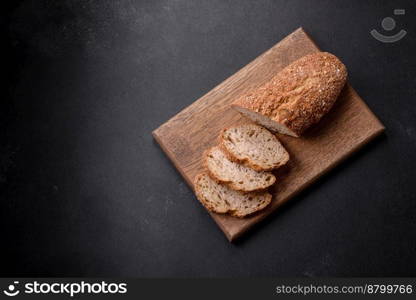  Delicious crispy bread with cereals cut into slices on a wooden cutting board on a dark concrete background