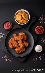 Delicious crispy breaded chicken wings grilled with spices and herbs on a dark concrete background