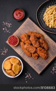 Delicious crispy breaded chicken wings grilled with spices and herbs on a dark concrete background