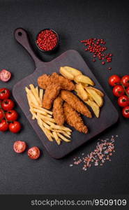 Delicious crispy chicken nuggets breaded with salt and spices on a dark concrete background